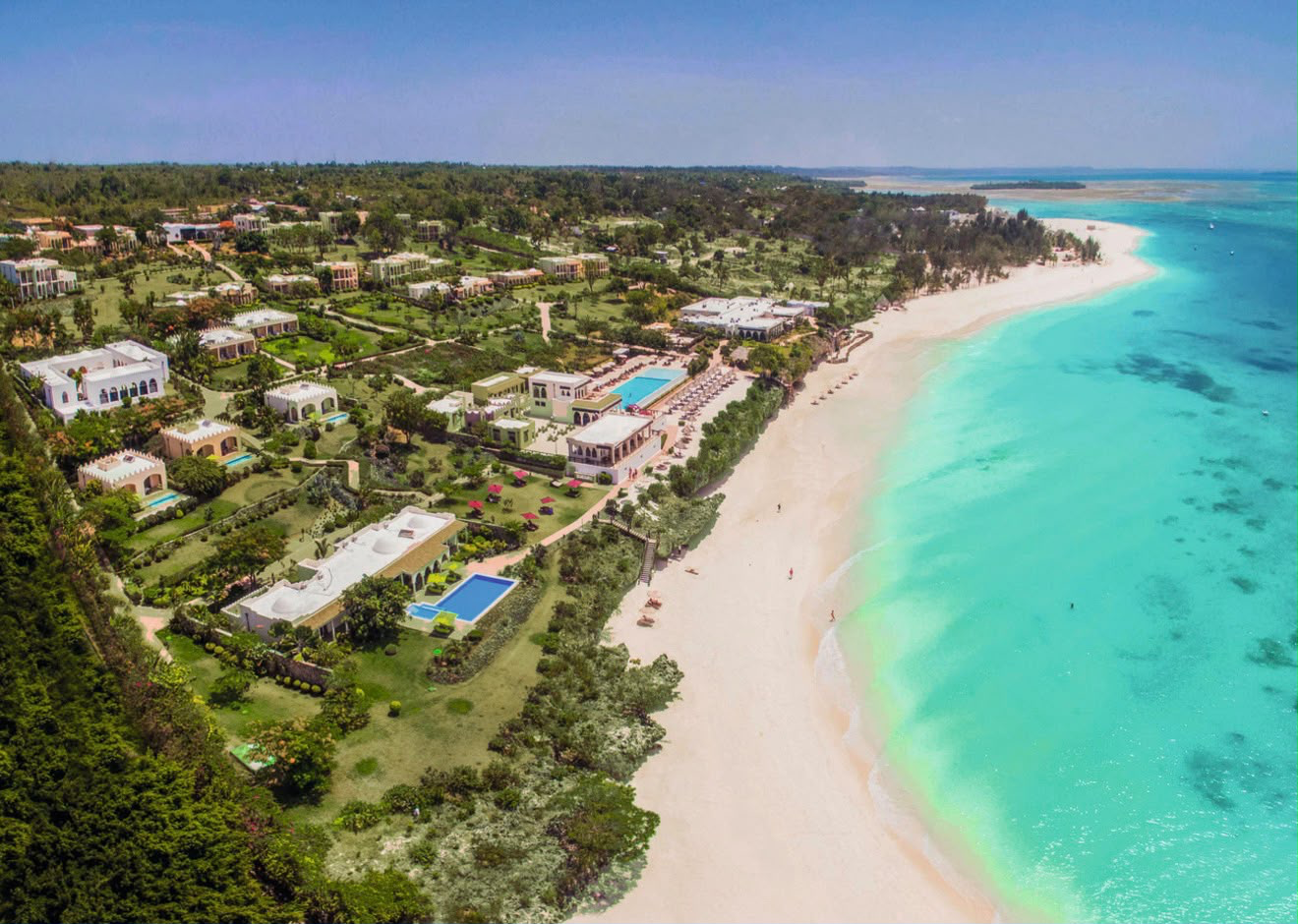 Aerial view of a tropical coastline beside turquoise Indian Ocean water.